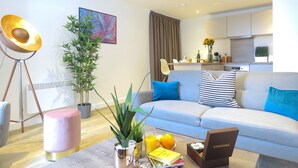 Een moderne woonkamer met een bank, salontafel en potplanten.