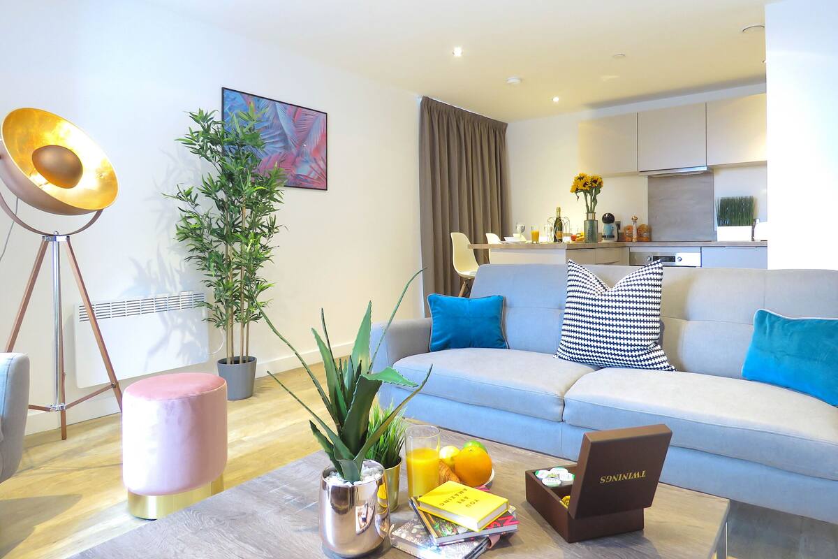 Een moderne woonkamer met een bank, salontafel en potplanten.