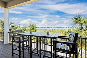 Relax in a serene outdoor setting with a table and chairs overlooking a tranquil body of water and distant shoreline.