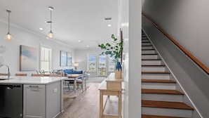 Een moderne keuken met een centraal eiland, houten vloeren en hanglampen.