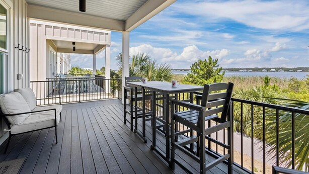 Een overdekt terras buiten met een tafel en stoelen, uitkijkend op een waterpartij en groen.