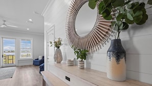 Een moderne woonkamer met een grote spiegel, een blauwe bank en een houten bankje.