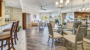 A spacious living area with a large dining table, comfortable seating, and a kitchen in the background. - 1BR Villa w/ Private Balcony Overlooking Beach (Hilton Head Island)