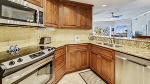 A modern kitchen with wooden cabinets, stainless steel appliances, and a herringbone tile backsplash. - 1BR Villa w/ Private Balcony Overlooking Beach (Hilton Head Island)