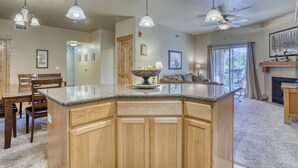 A spacious kitchen with a large island, wooden cabinets, pendant lights, and a fireplace.