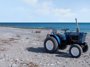 A blue tractor on a rocky beach with the sea in the background. - By The Beach- UK31201 (Downderry and Seaton, near Looe)