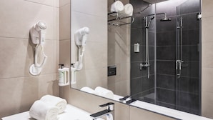 A modern bathroom with a white sink, two hair dryers mounted on the wall, a glass-enclosed shower, and a mirror reflecting the room. - B&B Hotel Lisboa Aeroporto (Loures)
