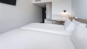 Una habitación de hotel moderna con una cama grande, un escritorio y una kitchenette pequeña.