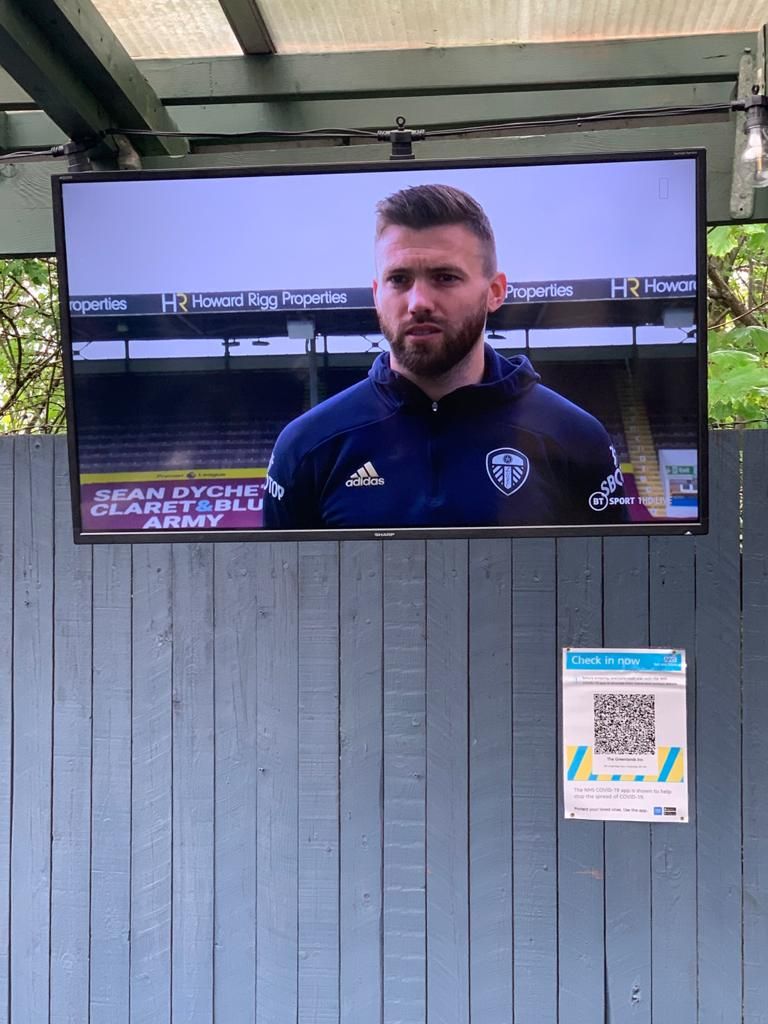 A television mounted on a wooden structure with a QR code and a sign.