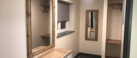 A hallway with a wooden desk, a mirror, and a coat rack.