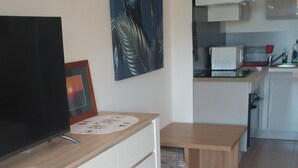 Eine moderne Küche mit weißen Schränken, einer Holzausziehtafel und einem großen Flachbildfernseher.