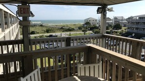 A balcony with a view of the beach and ocean, an exit sign, and a wooden railing. - Villa with Great Ocean View (Atlantic Beach)