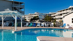 A swimming pool with lounge chairs and a covered seating area, surrounded by multi-story buildings with balconies. - Villa with Great Ocean View (Atlantic Beach)
