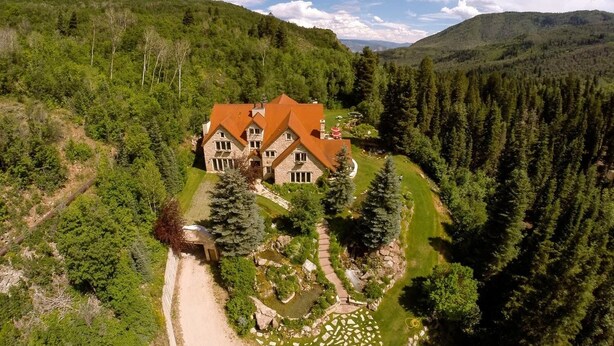A large, two-story house with a red roof, surrounded by dense forest and hills. - STONEHILL LODGE, SWIM, HIKE, SECLUSION, LUXURY (Midway)