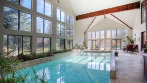 An indoor swimming pool with large windows, wooden beams, and a tiled floor. - STONEHILL LODGE, SWIM, HIKE, SECLUSION, LUXURY (Midway)