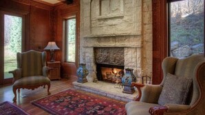 A cozy living room with a stone fireplace, wooden paneling, and a red patterned rug. - STONEHILL LODGE, SWIM, HIKE, SECLUSION, LUXURY (Midway)