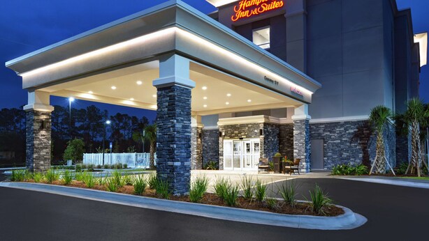 A Hampton Inn & Suites with a covered outdoor area, stone pillars, and a well-lit entrance. - Hampton Inn & Suites MacClenny I-10 (MacClenny)