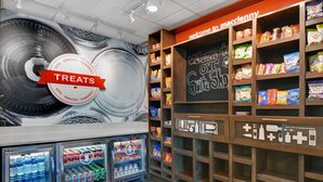 A snack and beverage section with refrigerated drinks and shelves of snacks. - Hampton Inn & Suites MacClenny I-10 (MacClenny)