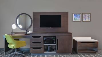 Ein modernes Hotelzimmer mit Schreibtisch, Stuhl, Fernseher und Kunstwerk an der Wand.
