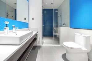 A modern bathroom with a large mirror, white sink, and toilet.