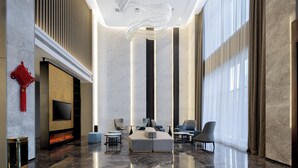Un'ampia hall dall'arredamento moderno, con una grande area salotto, un caminetto e un grande schermo televisivo.