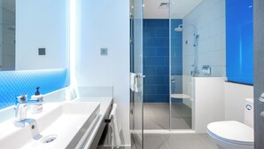 Un bagno moderno con cabina doccia in vetro, un lavandino bianco con dispenser di sapone e un water.