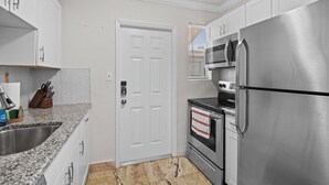 A modern kitchen with white cabinets, stainless steel appliances, and a granite countertop. - Davis Islands Urban Fiesta 2 Bedroom (Tampa)