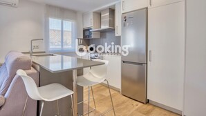 Eine moderne Küche mit einer zentralen Kochinsel, Barhocker, integriertem Backofen und einem Edelstahlkühlschrank.
