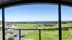 Blick aus einem Fenster auf einen Golfplatz, eine Wohngegend und eine Straße mit Fahrzeugen.