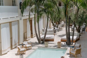 A poolside area with lounge chairs, a small pool, and palm trees. - Cara (Los Angeles)