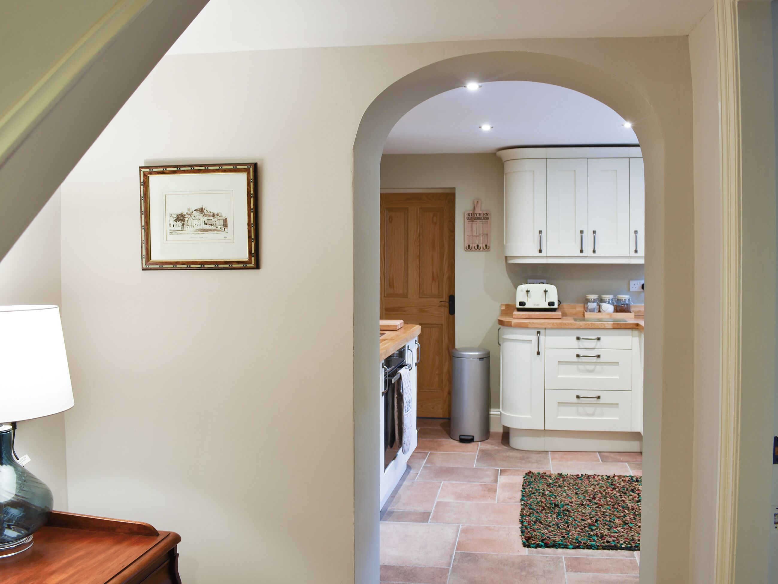 A kitchen with white cabinets, a toaster, and a trash can.