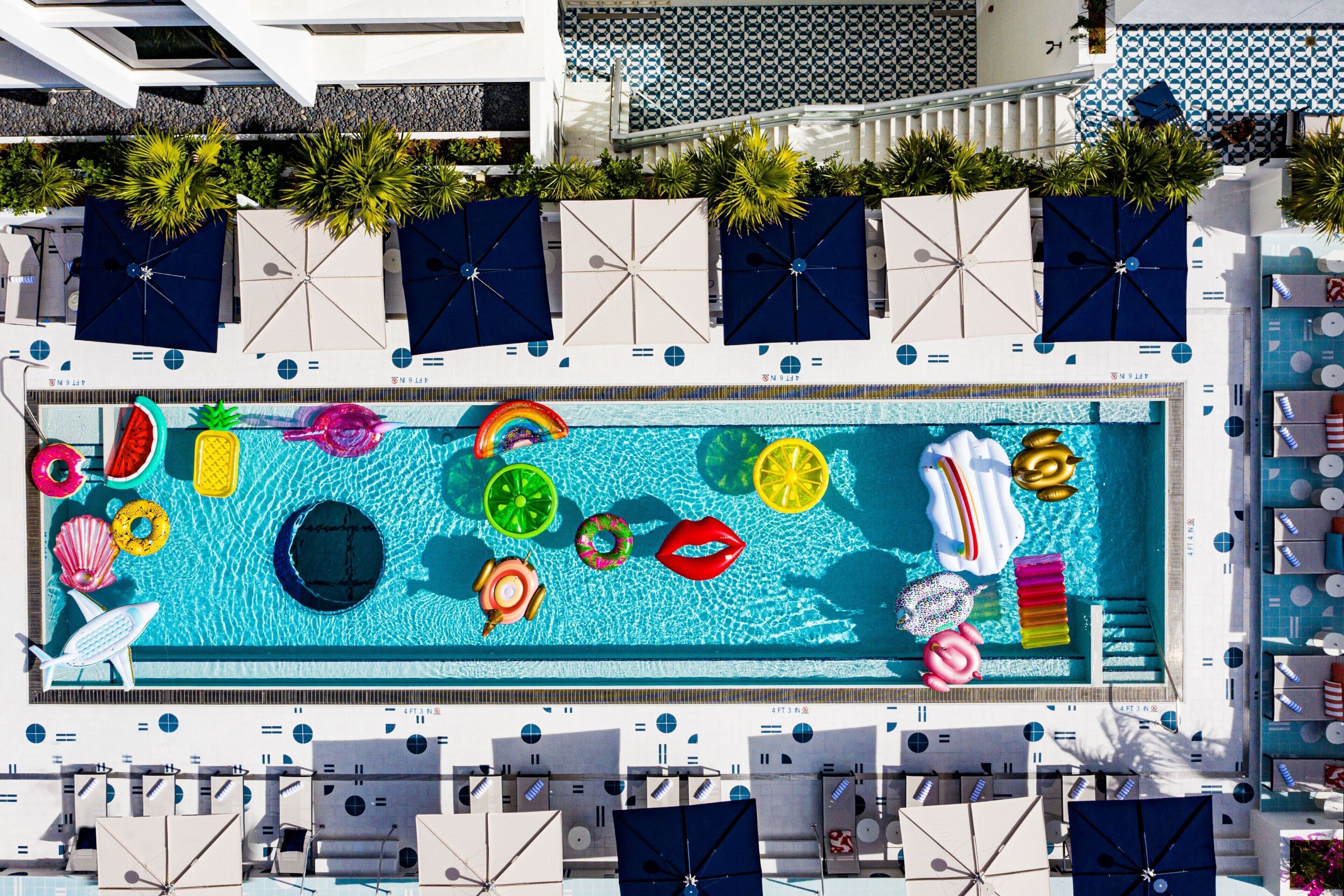 A rooftop pool with various floating objects and umbrellas.