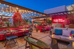 An outdoor dining area with red seating, tables, and a canopy.