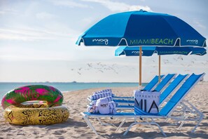 A beach scene with a blue umbrella labeled "MIAMI BEACH" and lounge chairs. - Moxy Miami South Beach (Miami Beach)
