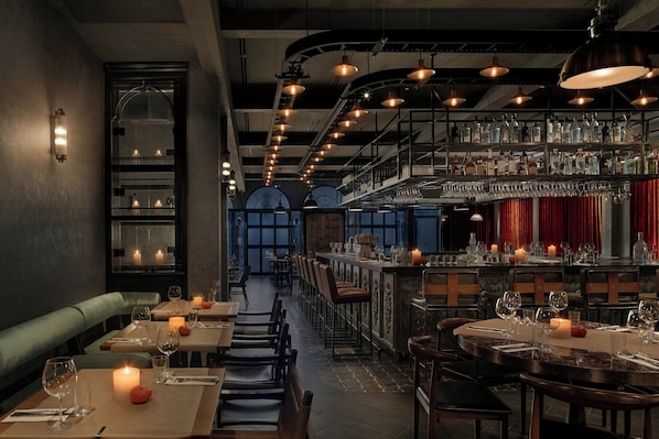 A restaurant with a bar area, tables set for dining, and a view through a window.