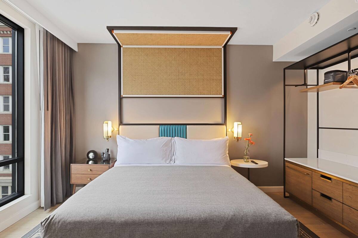 Une chambre d’hôtel avec un grand lit, des tables de chevet, une armoire et une vue sur la ville.