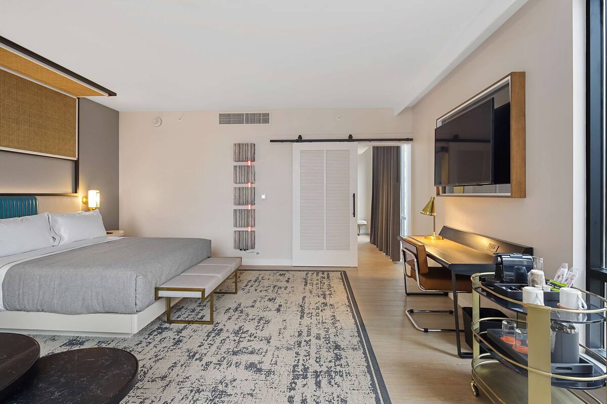 Une chambre d’hôtel moderne équipée d’un lit, d’un bureau et d’une télévision.