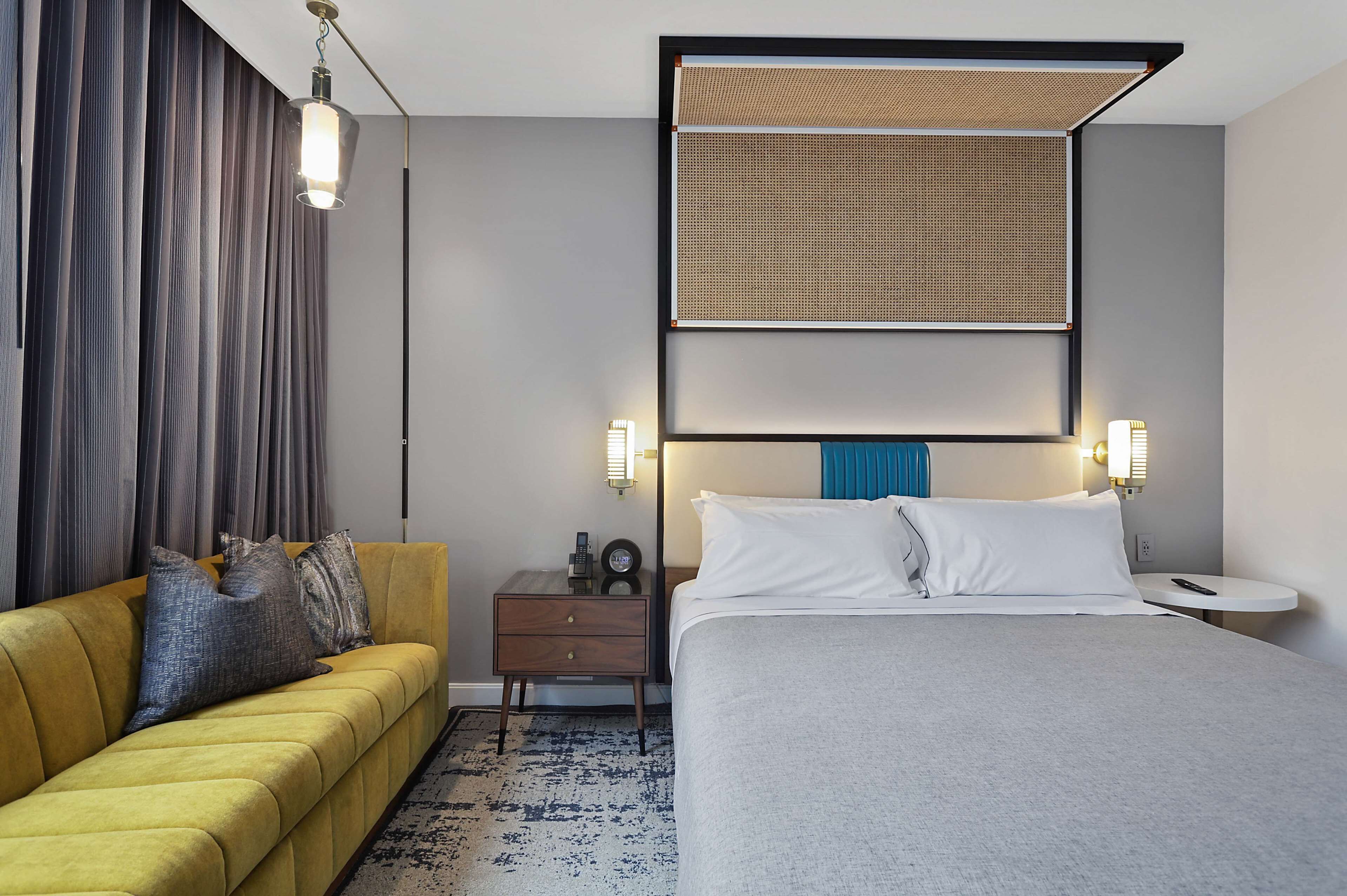 Ein Hotelzimmer mit Bett, einer Couch, einem Nachttisch und einem am Wand montierten Kopfteil.
