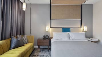 Ein Hotelzimmer mit Bett, einer Couch, einem Nachttisch und einem am Wand montierten Kopfteil.