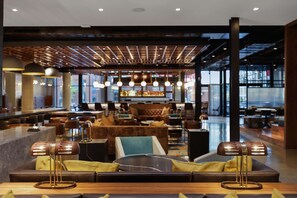 A modern lounge area with seating and a bar in the background. - Canopy by Hilton Memphis Downtown (Memphis)