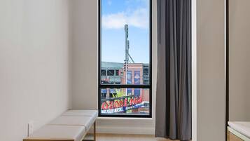 A room with a large window, a bench, and a view of a building with a sign that reads "OZONE PART".