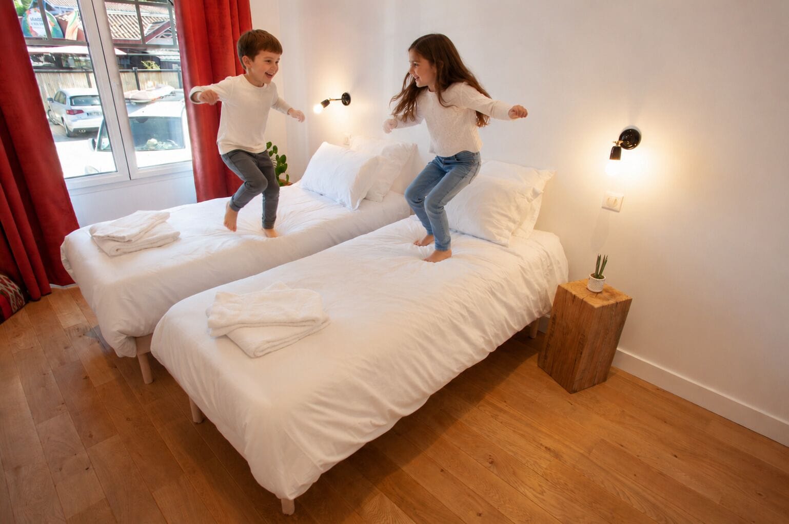 Ein Zimmer mit zwei Betten, einem Holznachttisch und einem Fenster mit Vorhängen.