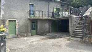 A two-story building with a balcony, a staircase, and a green door.