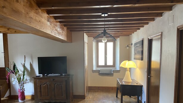 A wooden-floored room with a television, a lamp, and a window.