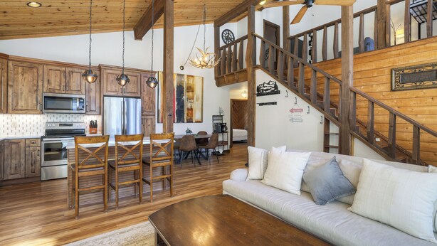 A spacious living area with a wooden staircase, a dining area, and a kitchen with modern appliances. - Dog Friendly, On Shuttle Route, Private Hot Tub, Near River, Walk to Town (Breckenridge)