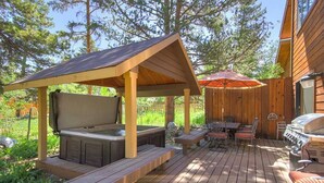 A wooden deck with a hot tub, outdoor seating, and a barbecue grill. - Dog Friendly, On Shuttle Route, Private Hot Tub, Near River, Walk to Town (Breckenridge)