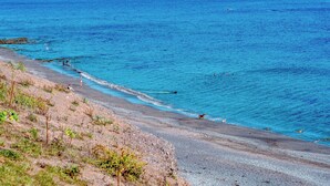 A beach with clear blue water, pebbles, and sparse vegetation. - Beachside, West Yardley House - UK31200 (Downderry and Seaton, near Looe)