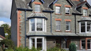 A two-story stone building with a bay window, a small porch, and a chimney. - 4 bedroom accommodation in Keswick (Keswick)