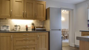 A modern kitchen with wooden cabinets, a stainless steel refrigerator, and a tiled backsplash. - 4 bedroom accommodation in Keswick (Keswick)