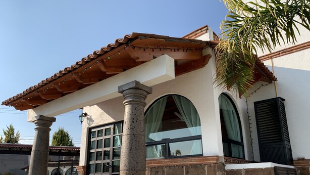 A building with a covered entrance, large windows, and a stone column. - Hotel Villas Mahando (Ezequiel Montes)